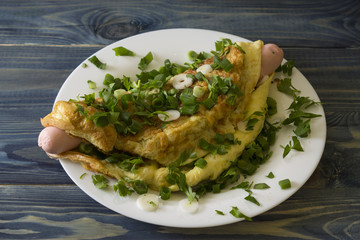 Omelette with sausages, cheese and greens on a white plate. Delicious and nutritious breakfast.