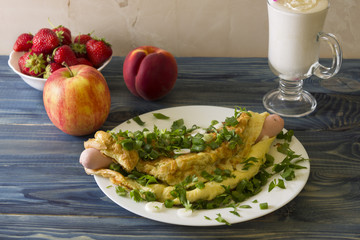 Omelette with sausages, cheese and greens on a white plate. Delicious and nutritious breakfast.