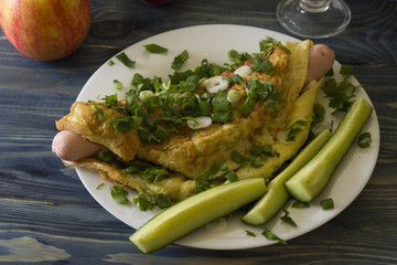 Omelette with sausages, cheese and greens on a white plate. Delicious and nutritious breakfast.