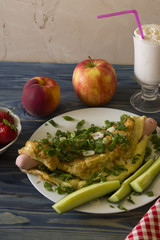 Omelette with sausages, cheese and greens on a white plate. Delicious and nutritious breakfast.