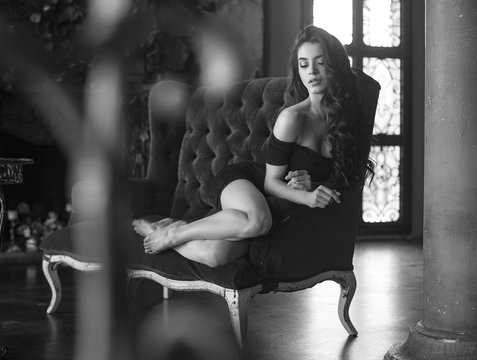 Spanish woman in a sexy little dress posing in a vintage interior. Beautiful girl in erotic pose. Black and white. Old Hollywood style. Retro photo.