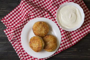 Cheese pancakes on a white plate and sour cream. Delicious dessert and hearty breakfast.