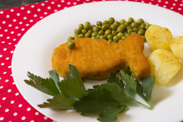 Fish cutlet on a white plate with potatoes and peas