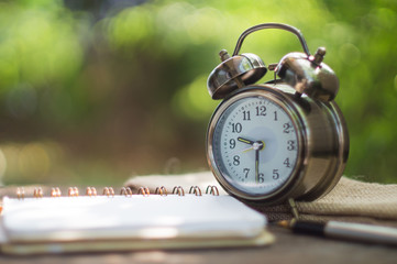 Blank  notebook with clock and pen on antique wood background