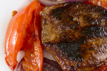 Fried meat with vegetables on a white plate. Tasty and nutritious dish.