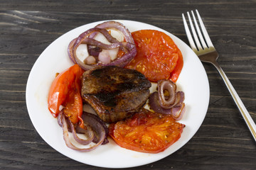 Fried meat with vegetables on a white plate. Tasty and nutritious dish.