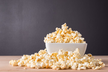 Popcorn in white bowl on wood background
