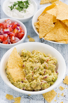 spicy avocado sauce and assorted sauces with corn chips, vertical, closeup