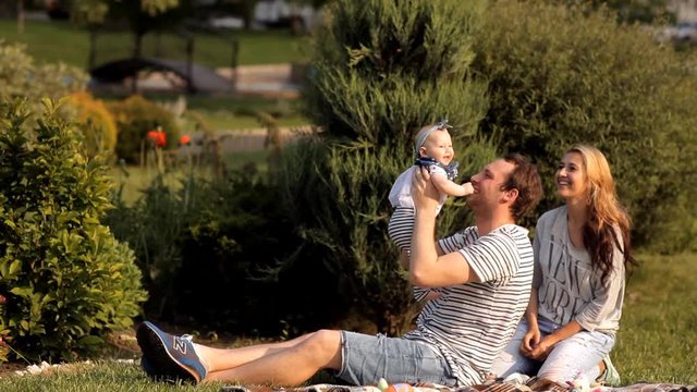 Young parents play with their child on a picnic in a recreation park