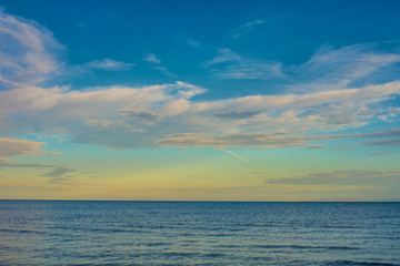 Naklejka na ściany i meble rippled surface of cold sea under sky with fluffy clouds at sunrise 