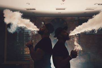 Two men vaping in an authentic room with brick walls