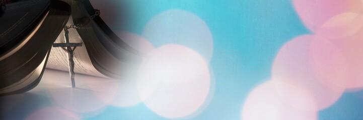 Rosary under bible and blue pink bokeh transition