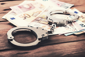 financial crime concept - money and handcuffs on the table - obrazy, fototapety, plakaty