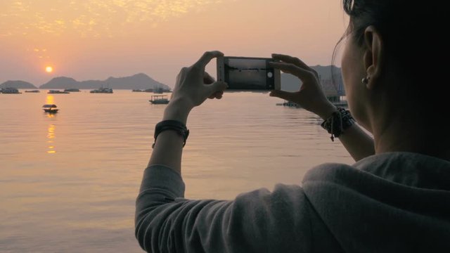 Attractive woman taking pictures of beautiful  views ofof Ha Long Bay at sunset