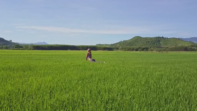 Aerial View Girl Sits in Yoga Pose on Rice Field by Hills