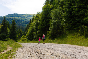Mother and little girl walking along the mountain road