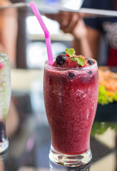 glass of blueberry smoothie with straw on glass table. Protein cocktail. Healthy drink. Fresh homemade smoothie. Healthy breakfast of smoothie, dessert, yogurt or milkshake