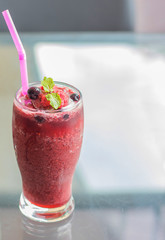 glass of blueberry smoothie with straw on glass table. Protein cocktail. Healthy drink. Fresh homemade smoothie. Healthy breakfast of smoothie, dessert, yogurt or milkshake