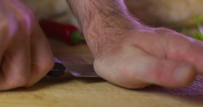 Man crushes garlic clove with flat knife blade. Slow motion