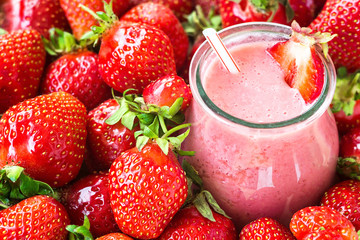 Beautiful appetizer red strawberry fruit smoothie. Yogurt cocktail. Close up. Natural detox. Liquid ice cream. Glass of strawberry milkshake with berries background, top view, selective focus.