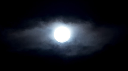 The moon in the haze of the clouds at night