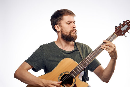 Young guy with a beard on a light background playing the guitar