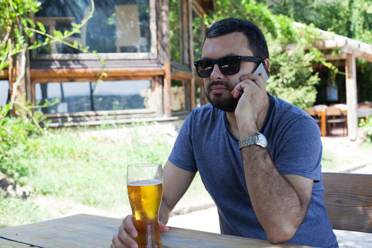 Man drinking beer and talking on mobile phone