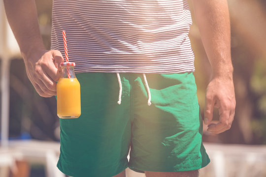 Close up of man holding fresh orange juice. Healthy eating and summertime concepts.
