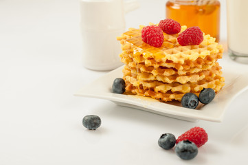 Homemade waffles with berries in plate on grey table