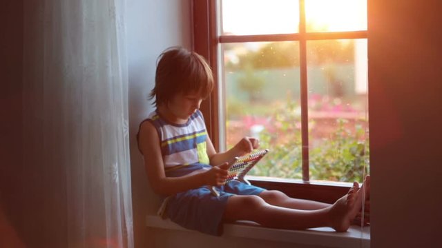 Cute little toddler child, playing with abacus on a window