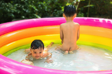 Children play water in colorful kiddie pool with nature background. Isolated and clipping path