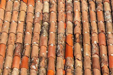 Part of tile on the roof of a house building, closeup. A red tiled terracotta roof. The orange roof tiles, maps and textures. Texture of tiles. Background with part of roof. Rows of roof bricks.