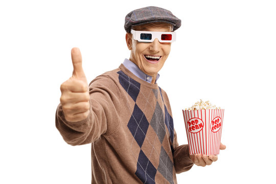 Senior with 3D glasses and popcorn making thumb up sign