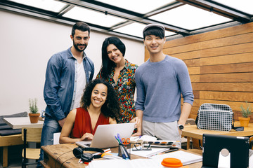 Fototapeta na wymiar Startup of four multiethnic happy people in a modern coworking espace