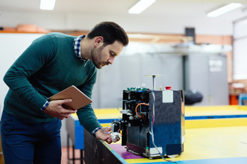 Fototapeta na wymiar Young engineer testing his robot in workshop