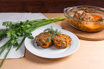 Rissole of pork served on a white plate and herbs - dill, green onion, parsley around the plate.