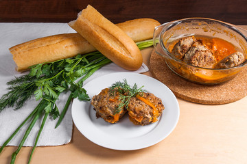 Rissole of pork served on a white plate with white wheat bread and herbs - dill, green onion, parsley around the plate.