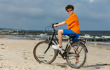 Fototapeta premium Teenage boy biking on beach 