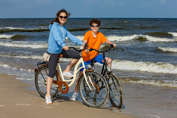 Teenage girl and boy biking on beach 