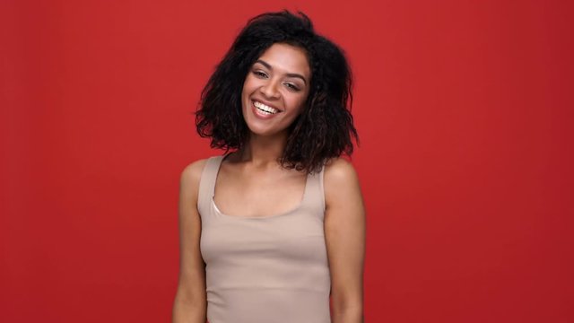Young pretty african woman laughing over red background