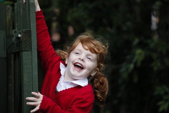 Little girl, age 4, wearing her school uniform in a garden.
