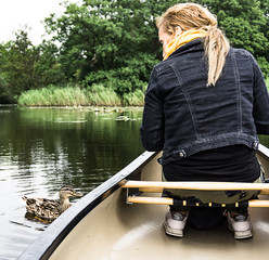 junge Frau im Kanu lockt eine Stockente an