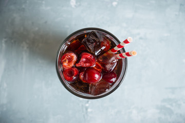 Refreshing cold cherry cola on the wooden background