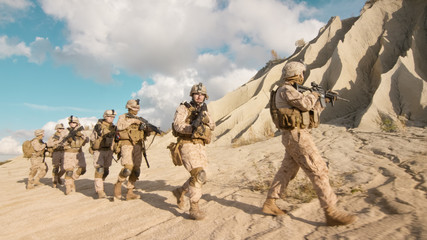 Squad of Fully Equipped and Armed Soldiers Walking in Single File in the Desert.