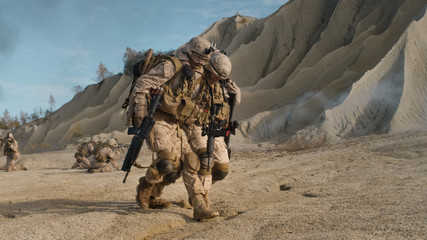 Soldier Carrying Injured One While other Members of Squad Covering Them During Military Operation in the Desert.
