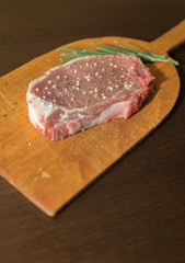 Raw pork steak with salt pepper ans rosemary on wooden board