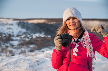 Girl tourist in a red jacket photographs the winter landscape on the camera. The tourist takes off...