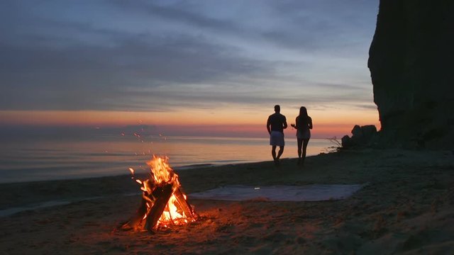 Silhouette of a man and a female on the beach they drink wine from glasses
