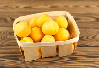 Ripe fresh apricot in basket on rustic wooden background