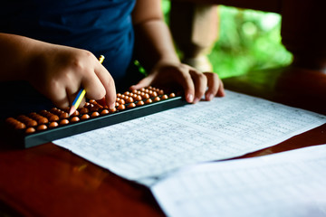 Cute little girl playing with abacus at home. Smart child learning to count.